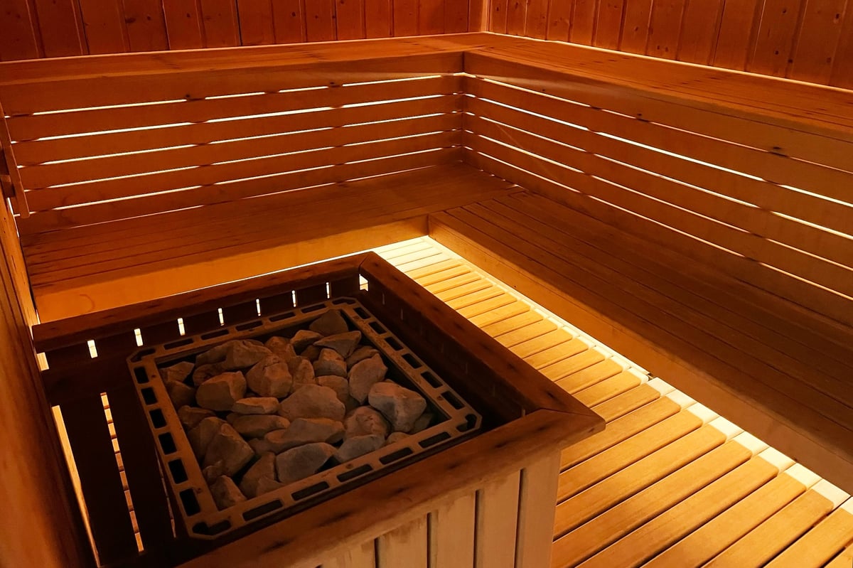 Warm wooden sauna interior with pebbles and benches