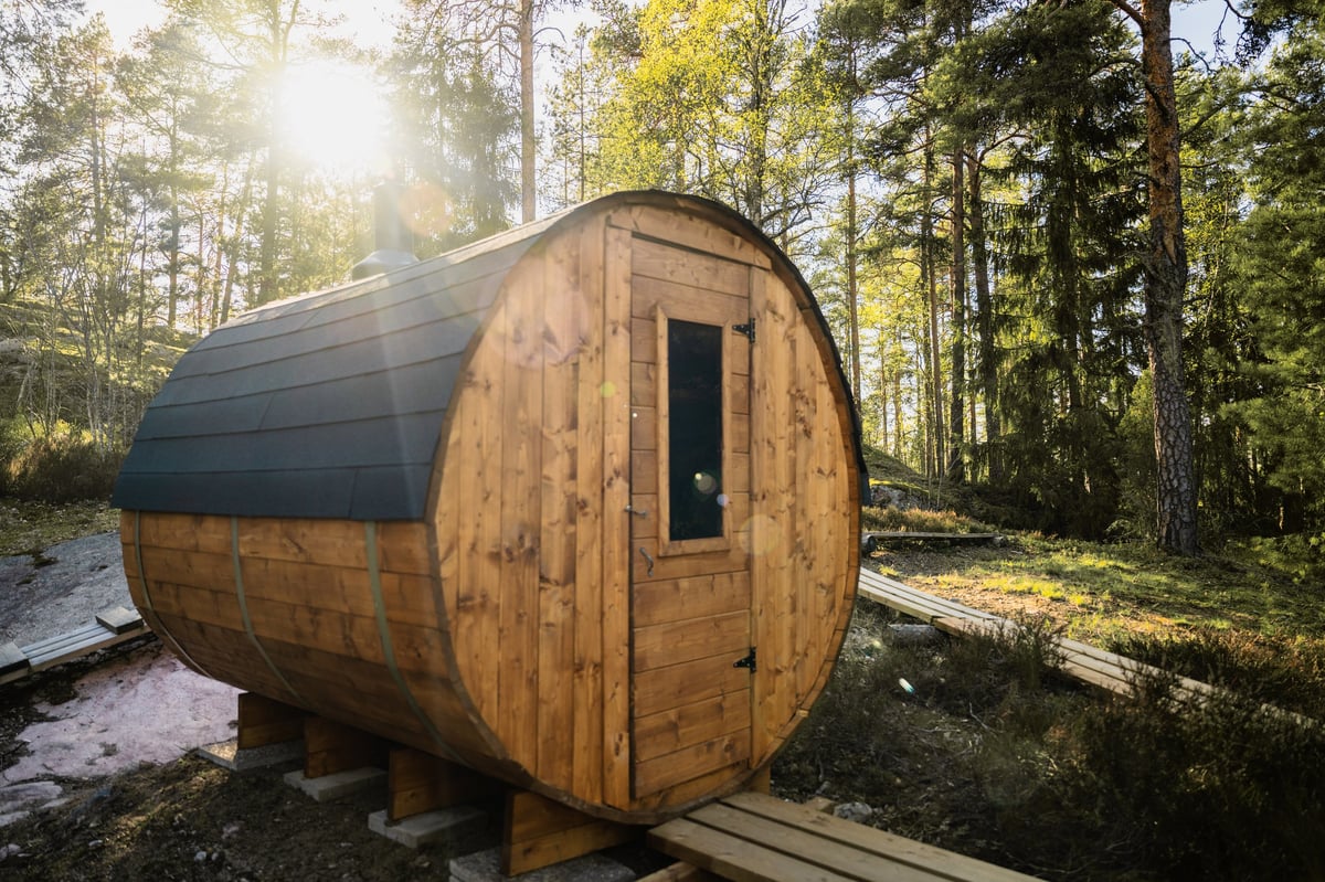 Traditional wooden barrel sauna set in a quiet forest landscape