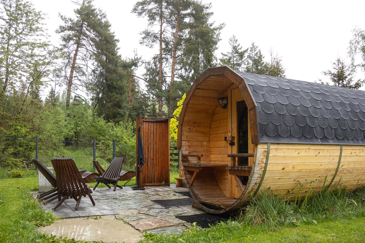 Barrel sauna and outdoor bathing area in a wooded setting